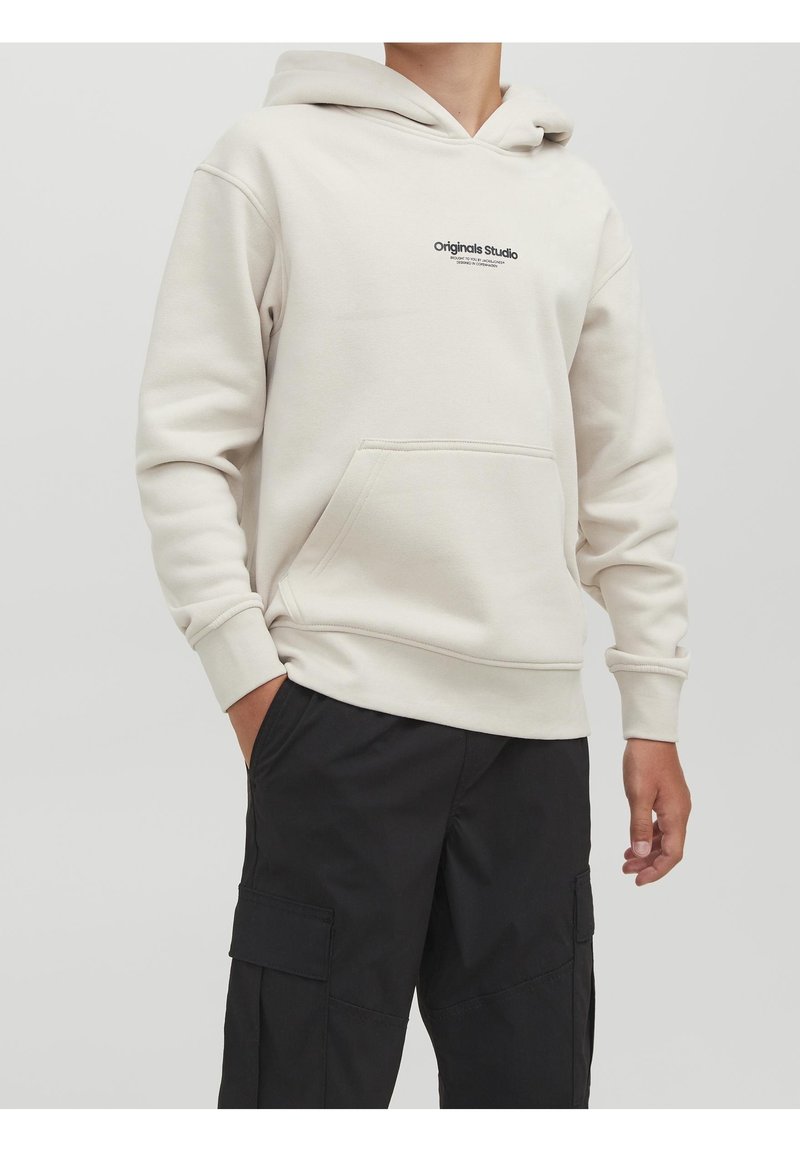 Kremfarvet hoodie med frontlomme og justerbar snøre i hætten. Har en lille sort logo på brystet. Kombineret med sorte cargobukser.