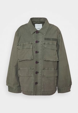 Jasnozielona kurtka zapinana na guziki z czterema przednimi kieszeniami z klapkami, kołnierzykiem i długimi rękawami, ułożona płasko na białym tle.