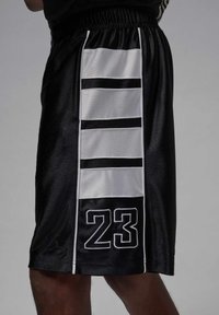 Shorts de sport noirs avec une texture lisse, présentant des rayures blanches sur le côté et le numéro "23" en blanc contrastant en bas.