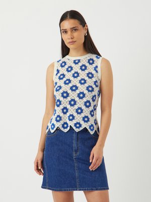 Crochet top na ramínka ve modro-bílém květinovém vzoru, s vlněným lemem, v kombinaci s džínsovou sukní. Hladká textura, přiléhavý střih.
