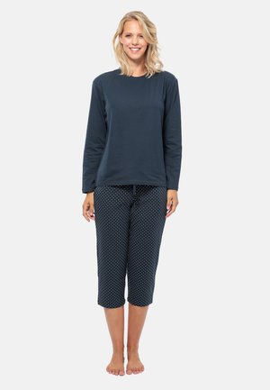 Marinblå långärmad topp med rund halsringning, kombinerad med korta byxor med ett vitt prickmönster. Tillverkad av mjukt tyg.