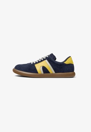 Granatowe zamszowe sneakersy z żółtymi i srebrnymi akcentami, okrągły czubek, beżowa gumowa podeszwa i białe sznurówki do zapięcia. Boczna część ma wyprofilowany kształt.