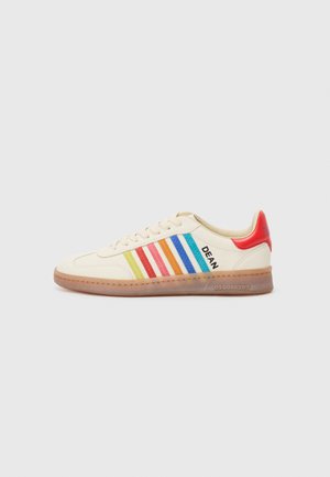 Baskets de couleur crème avec des rayures multicolores en rouge, jaune, vert et bleu, dotées d'un talon rouge et du nom « DEAN » sur le côté.