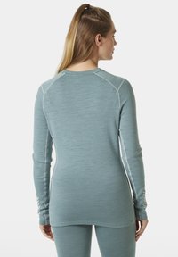 Langemouwen sporttop in lichtblauw met ribbeltextuur. Kenmerkt zich door contrasterende stiksels en een gebogen zoom, ontworpen voor comfort tijdens activiteiten.