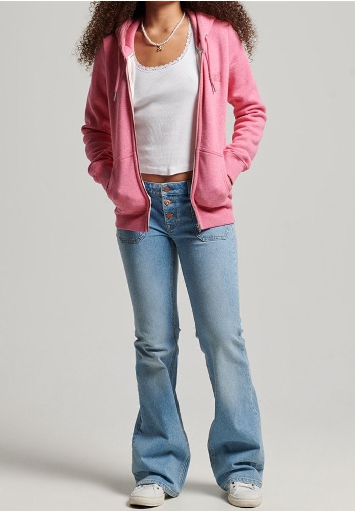 Sudadera rosa con cremallera frontal y cordón, combinada con pantalones de mezclilla acampanados en azul claro con detalles de botones. Estilizada con zapatillas blancas.