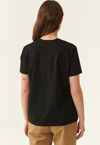 Sort bomulds T-shirt med korte ærmer, rund halsudskæring, afslappet pasform og glat tekstur. Ingen synlige logoer eller mønstre.