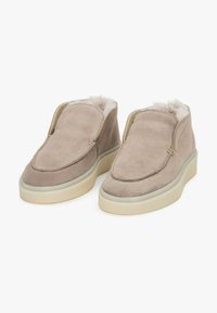Suède instappers in lichtbeige met een zachte fleece voering, ronde neus en crèmekleurige rubberen zolen. Minimalistisch ontwerp met handgestikte accenten.
