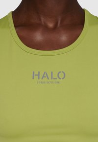 Jasnozielony top na ramiączkach z okrągłym dekoltem, z szarym logotypem "HALO" oraz cyframi nadrukowanymi z przodu. Gładki, elastyczny materiał.