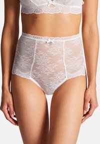 Culotte taille haute en dentelle blanche avec motif floral, ceinture fine et bords festonnés. Possède un petit accent en ruban à l'avant.