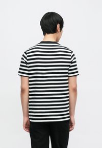 Koszulka w paski w czarno-białe, z krótkim rękawem, klasyczny okrągły dekolt, wykonana z bawełny, o prostym kroju i miękkiej fakturze.