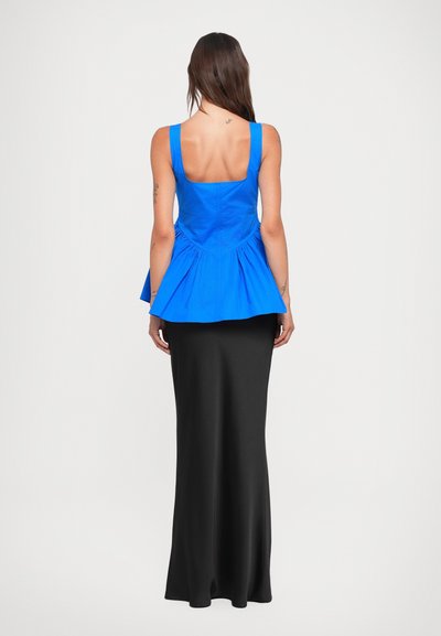 Blue peplum top with a square back, paired with a long black skirt. Smooth fabric with a fitted silhouette and flared hemline.