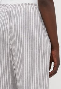 Pantaloni in lino leggeri a righe, caratterizzati da un morbido elastico in vita, righe verticali grigie e bianche e una vestibilità ampia.