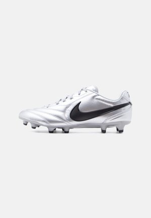Λευκό ποδοσφαιρικό παπούτσι με μαύρο λογότυπο Nike Swoosh και διαμορφωμένα καρφιά στην σόλα, εμφανίζεται από το πλάι σε απλό φόντο.