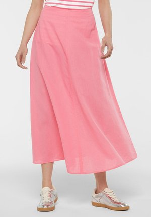 Pink, flowy A-line skirt made from lightweight material, featuring a high waist and hemline that falls below the calf, paired with casual shoes.