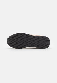 Černá gumová podrážka s cikcak vzorem, která má texturovaný povrch a mírné prohnutí na patě.