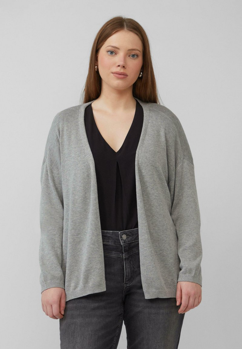 Grauer Cardigan aus weichem Strickstoff mit lockerer Passform, offenem Front und gerippten Ärmeln, kombiniert mit einem schwarzen Oberteil und dunklen Jeans.
