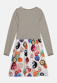 Gestreepte jurk met lange mouwen, met een effen zwart en crèmekleurig bovenstuk en een kleurrijke, geprinte flared onderkant met vredestekens en glimlachende gezichten.