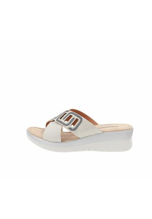 Sandal in neoprene bianco con cinturini incrociati. Presenta un accentuatura testurizzata in argento e una suola in schiuma confortevole con un leggero tacco a zeppa.