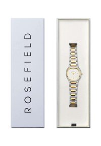 Reloj Rosefield en una caja blanca. Presenta una esfera redonda blanca, acentos dorados y una pulsera metálica bicolor en plata y oro con eslabones rectangulares.