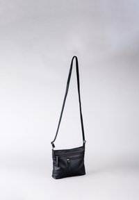 Black leather crossbody bag with adjustable strap, featuring two zippered front pockets and a sleek design. Smooth texture and minimal accents.
