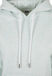 Felpa con cappuccio di colore azzurro chiaro realizzata in un morbido tessuto testurizzato. Presenta una tasca a marsupio frontale, lacci bianchi e punte argentate.