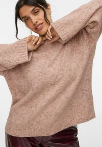 Pull en laine rose doux et texturé, avec une coupe décontractée, des poignets côtelés et une silhouette légèrement oversize. Agrémenté de détails légèrement mouchetés.