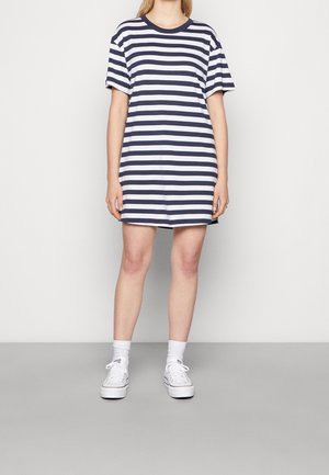 Sukienka t-shirt w paski w kolorze granatowym i białym, wykonana z miękkiej bawełny. Posiada okrągły dekolt i luźny krój, sięgająca do połowy uda. Białe sneakersy.