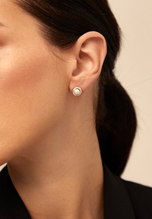 Pendientes de plata con un prominente perla redonda, colocada dentro de un bisel circular liso. El diseño es clásico y minimalista.