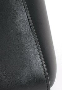 Surface en cuir noir avec couture détaillée le long d'une couture, montrant la texture et une finition lisse.