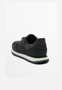 Sneaker in suede nero con punta arrotondata, dettagli testurizzati e suola intermedia bianca. Presenta una suola in gomma con trazione.