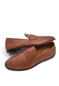 Brune læder loafers med en rund tå, syning detaljer og en frontrem. Glat tekstur med en lav, sort gummisål.