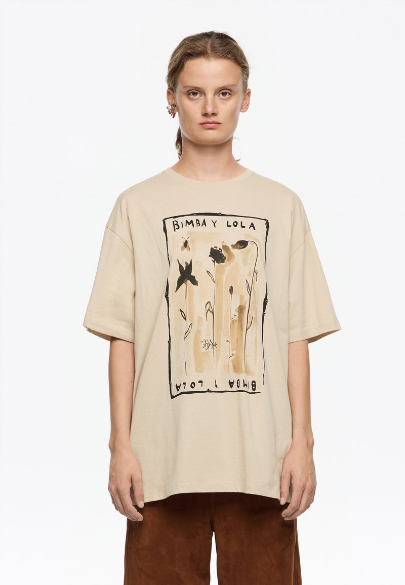 Beige suurenev t-särk musta ja pruuni lilleillustratsiooniga, mis on raamitud mustast kontuurist. Lühikesed varrukad ja ümar kaelus.