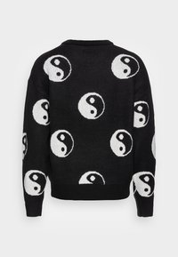 Schwarzer Strickpullover mit wiederholten weißen Yin-Yang-Mustern. Rundhalsausschnitt, gerippte Bündchen und Saum. Weiche Textur mit lockerem Schnitt.