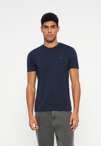 Ναυτικό μπλε βαμβακερό T-shirt με στρογγυλή λαιμόκοψη και κοντά μανίκια, διαθέτει ένα μικρό λογότυπο στο στήθος. Λείο υλικό και κανονική εφαρμογή.