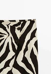 Gonna a righe zebrate in bianco e nero con una texture liscia, caratterizzata da due bottoni circolari neri sul davanti e un orlo rifinito con cura.