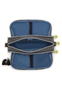 Grå och blå tygpouch med dragkedja i rektangulär form. Har dubbla fack, en nyckelring med en svart pom-pom och dragkedjehandtag i klar gul färg.