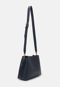 Marinblå läder axelväska med en strukturerad form, justerbar rem, detaljer i guldmetall och en sidetikett.