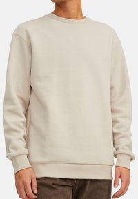 Lichtbeige sweatshirt met ronde hals, heeft ribgebreide manchetten en onderkant, gemaakt van zacht materiaal, met een relaxte pasvorm en zonder zichtbare logo's of patronen.
