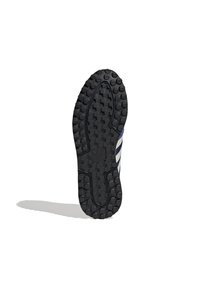 Černá gumová podrážka tenisky s texturovaným povrchem s kruhovými a šestiúhelníkovými vzory, označená logem pro lepší přilnavost a trakci.