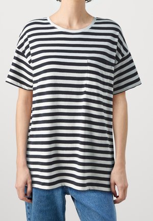 Personne portant un t-shirt à manches courtes rayé horizontalement noir et blanc avec une petite poche poitrine et un jean bleu.