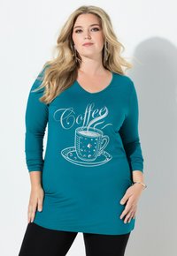 Długa tunika z długim rękawem w kolorze morskim, z dekoltem w serek, ozdobiona srebrnym nadrukiem filiżanki do kawy z dekoracyjnymi akcentami, o luźnym kroju. Połączona z czarnymi legginsami.