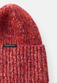 Strickmütze in Orangetönen und Rot, mit einem strukturierten Muster, umgeschlagenem Saum und einem schwarzen Etikett mit "PeakPerformance"-Markierung.