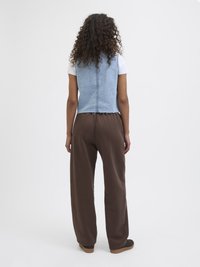 Denimvest med en kort design, lys blå farge, rå nederkant, kombinert med mørkebrune, løse bukser og brune sko.