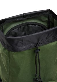Sac à dos vert avec fermeture à cordon noir et doublure intérieure noire montrant un motif à carreaux discret.