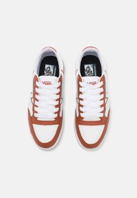 Vans sneakers med en hvit skinnoverdel med brune skinnakenter, rund tå, hvite snørebånd og perforerte detaljer på tåboksen.