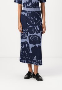 Fustă midi tricotată, cu un fond albastru închis și modele florale albastre deschise. Textură moale, cu un talie ajustată, asortată cu loafers negri.