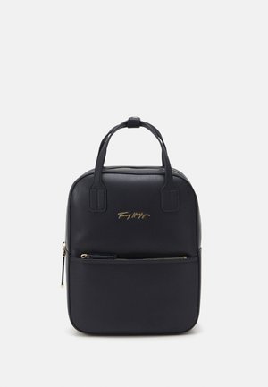 Sac à main rectangulaire noir avec deux poignées, poche avant zippée et lettrage logo doré sur une surface en cuir lisse.