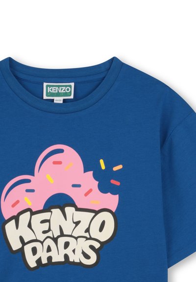 T-shirt en coton bleu présentant un motif de beignet rose avec des vermicelles colorés et un texte "KENZO PARIS" en noir, en gras, sous le dessin.