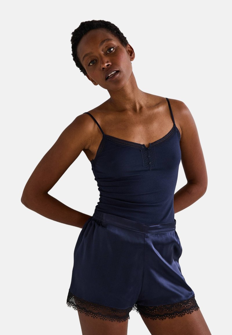Camisole en satin marine avec des garnitures en dentelle et des détails de boutons, assortie avec un short correspondant orné d'accents en dentelle sur l'ourlet.