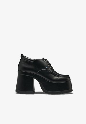 Fekete, vastag platformos cipő vastag, magas sarkú, fűzős elülső résszel és moc toe varrással, oldalnézetben, fehér háttéren.